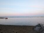 Calm blue sea with a pink blue sky and pebble beach